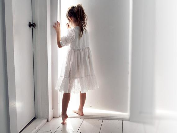 Dziewczynka otwierająca białe drzwi 